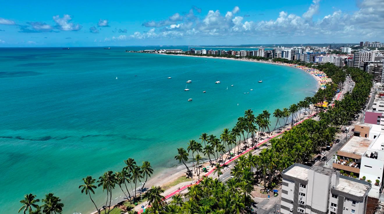 Vista aérea da orla de Maceió, com mar verde-azulado e coqueiros
